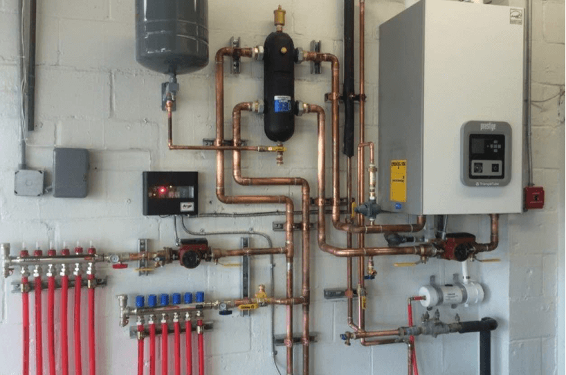 A wall with boiler and fittings on it